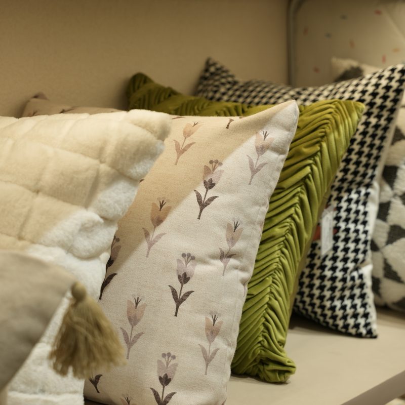 Embroidered, tasselled and houndstooth cushions on a display shelf at Drape Shoppe