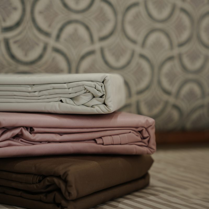 Folded bedsheets in ivory, blush and brown at Drape Shoppe