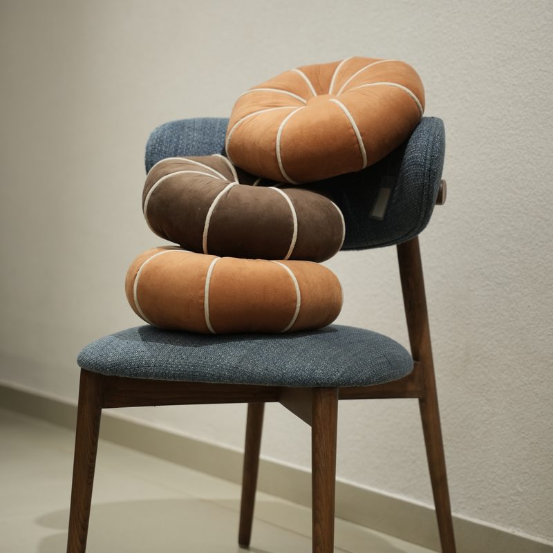 Round leather floor cushions stacked on a dining chair at Drape Shoppe