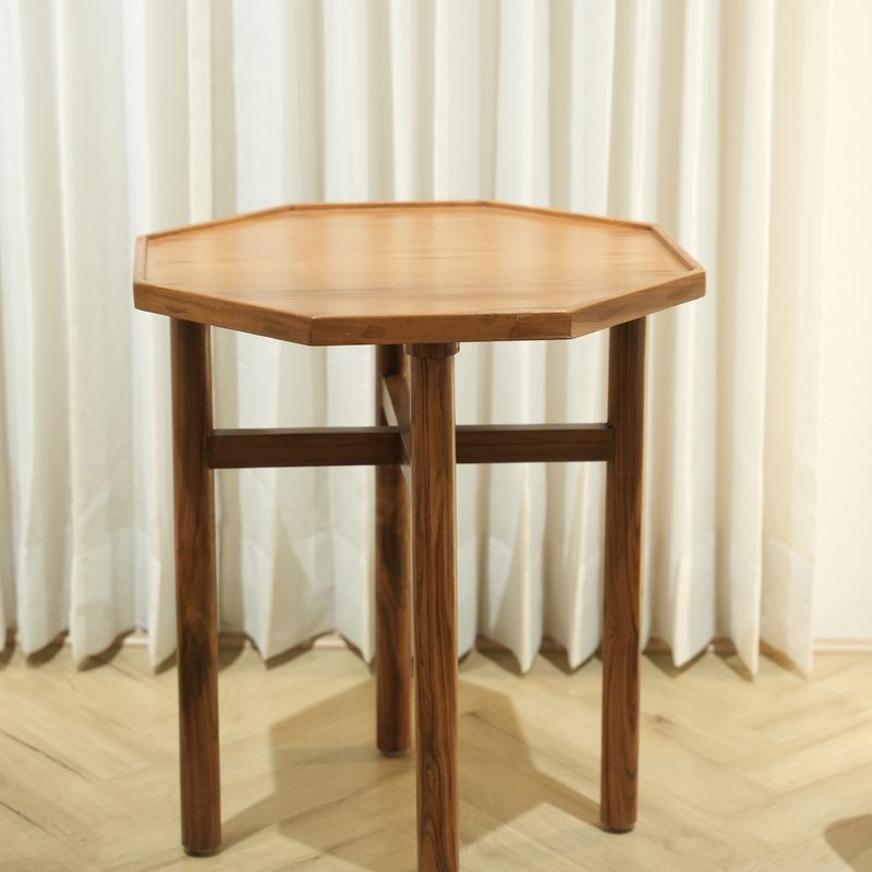 Octagonal wooden side table in front of sheer curtains at Drape Shoppe
